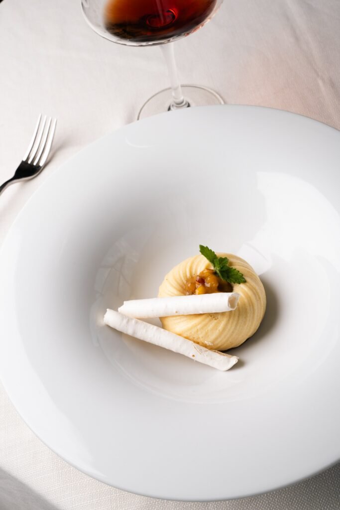 Dessert with cream, wafers and mint served at the table beside a glass of sweet wine