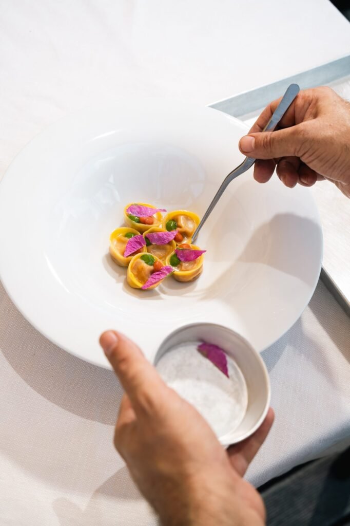 Impiattamento dei tortelli con fiori eduli e salsa